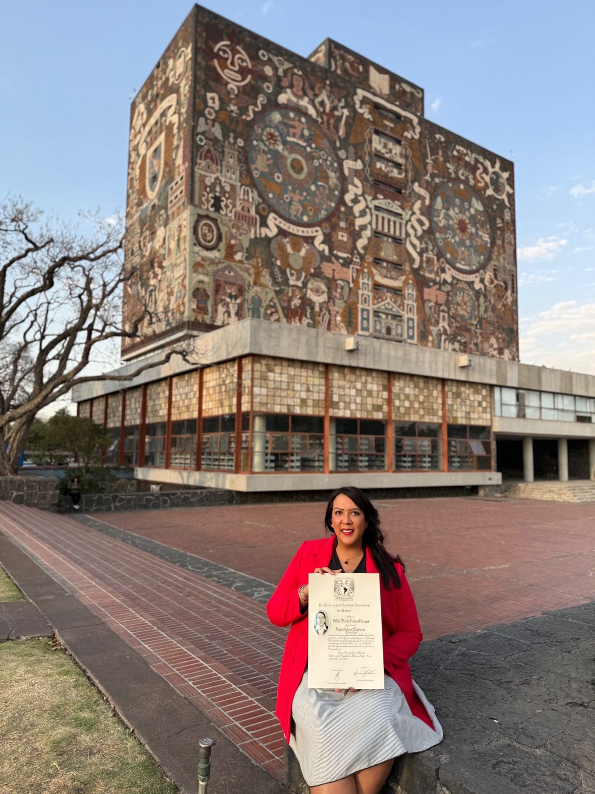 Dra. Silvia Sandoval con título frente a la biblioteca de la UNAM